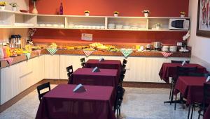 Ein Restaurant mit Tischen mit lila Tischdecken vor einer Theke in der Unterkunft Domus Hotel Cidade Nobre - Ipatinga in Ipatinga