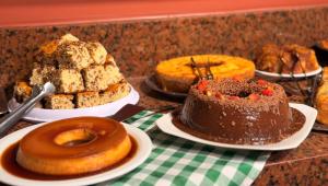 ein Tisch mit verschiedenen Arten von Kuchen und Gebäck in der Unterkunft Domus Hotel Cidade Nobre - Ipatinga in Ipatinga