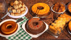 ein Tisch voller verschiedener Kuchen und Gebäcksorten in der Unterkunft Domus Hotel Cidade Nobre - Ipatinga in Ipatinga