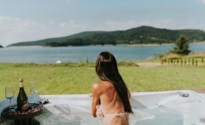 a woman in a bath tub with a bottle of wine at Aqua Glamp in Jaszczurowa +28 photos
