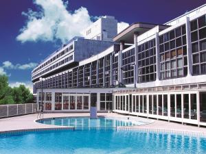 a large building with a swimming pool in front of it at Okudogo Ichiyunomori in Matsuyama