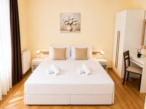 a white bedroom with a large white bed with two pillows at Villa Eloris in Pismenovo