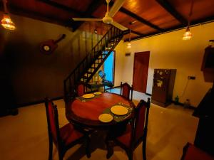 a dining room table with chairs and a spiral staircase at Senaro Villa in Sigiriya