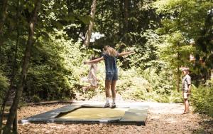 a girl standing on a trampoline in the woods at Das Kaltenbach - ApartHotel in Kaltenbach +36 photos