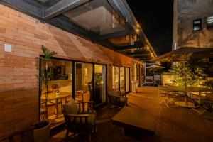 a patio with tables and chairs and a brick building at One House by Anora Spaces in São Paulo