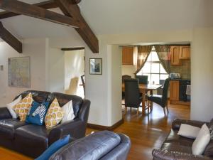 a living room with a leather couch and a dining room at Combe Cottage-Uk42228 in Low Borrowbridge