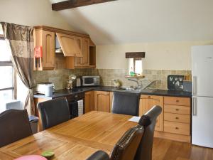a kitchen with a wooden table and a white refrigerator at Combe Cottage-Uk42228 in Low Borrowbridge