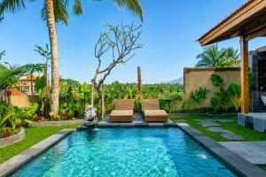 a backyard with a pool with two chairs and palm trees at Kubu Tama Villa in Tegalalang