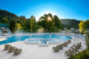 a large swimming pool with chairs around it at Terme Topolsica - Hotel Vesna in Topolšica