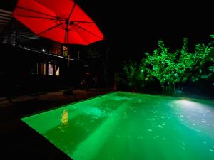 a red umbrella over a swimming pool at night at Senaro Villa in Sigiriya