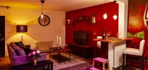 a living room with red walls and a couch and a tv at La Suite Privée - Maison Privative Spa & Sauna in Évreux