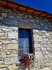 a window on a stone building with flowers in a window box at Casa S'urtzula in Sini +23 photos