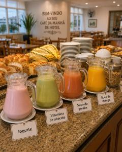 a counter with different types of jars of different colored liquids at Hotel Teofilo Otoni in Teófilo Otoni