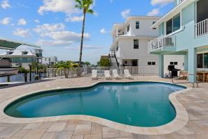 a swimming pool in front of a house with a palm tree at Beach Nuts by Sun Palace Vacations in Fort Myers Beach
