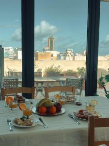 a table with plates of fruit on it with a view at Malta Crown guesthouse in St. Julianʼs