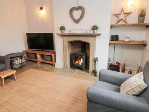 a living room with a fireplace and a tv at Canny Cottage in Belford
