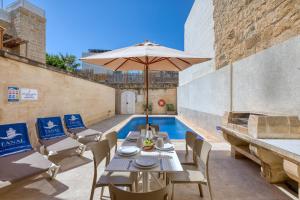 a patio with a table and umbrella next to a pool at Ta' Gianni in Xewkija