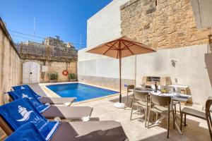 a patio with chairs and an umbrella and a pool at Ta' Gianni in Xewkija