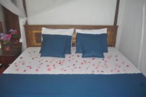 a bed with blue pillows and red flowers on it at Talalla Mango House in Talalla South