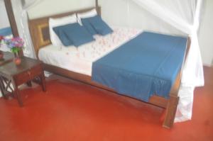 a bedroom with a bed with blue sheets and a table at Talalla Mango House in Talalla South +32 photos