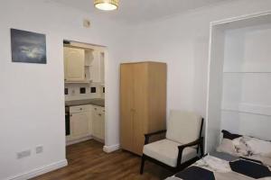 a bedroom with a bed and a chair and a kitchen at Newly Renovated Studio in Bishop's Stortford in Bishops Stortford
