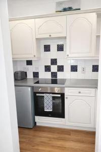 a kitchen with white cabinets and a stove top oven at Newly Renovated Studio in Bishop's Stortford in Bishops Stortford +7 photos