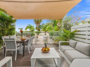 a patio with a couch and a table and chairs at Shell Beach Splendide 2 chambres sur la plage in Baie Nettle
