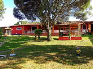 a yard with a red house and a tree at Chale da Pousada Curió in Ibiúna
