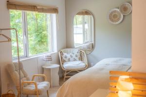 a bedroom with a bed and a chair and a mirror at Lalafofofo in Biei