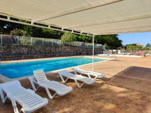 un gruppo di sedie a sdraio e una piscina di Camping du Vignal a Lablachère