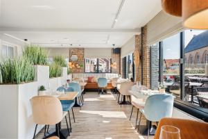 a restaurant with tables and chairs and windows at Strandhotel Zoutelande in Zoutelande