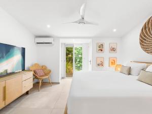 a white bedroom with a large bed and a tv at Shell Beach Splendide 2 chambres sur la plage in Baie Nettle +19 photos