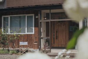 a house with a wooden door and a chair at Lalafofofo in Biei