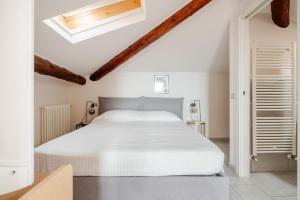 a white bedroom with a bed and a skylight at Lake View - Gardone Center - Private Garage in Gardone Riviera