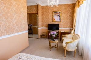 a room with a bed and a tv and a chair at Boutique Spa Casino Hotel Lybid Plaza in Khmelnytskyi
