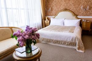 a bedroom with a bed and a vase of purple flowers on a table at Boutique Spa Casino Hotel Lybid Plaza in Khmelnytskyi +67 photos