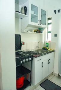 a kitchen with white cabinets and a stove top oven at Omtush Suites 002 in Marimbeti