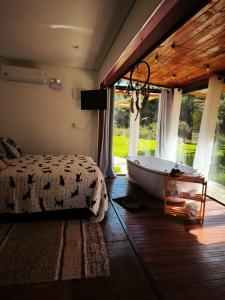 a bedroom with a tub and a bed and a window at Chalés Recanto dos Sonhos in Camanducaia