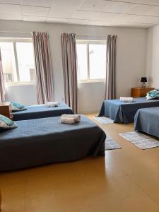 a room with three beds and two windows at Malta Crown guesthouse in St. Julianʼs