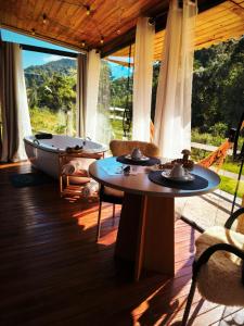 a room with two tables and a bath tub on a porch at Chalés Recanto dos Sonhos in Camanducaia