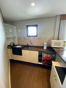 a small kitchen with a sink and a microwave at Flat - Excelente localização e vista espetacular in São José dos Campos +8 photos
