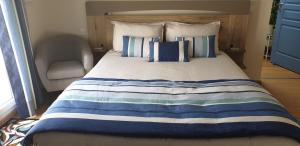 a bed with a blue and white striped blanket and a chair at La terrasse des oiseaux in Taillet