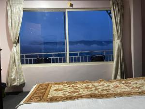 a bedroom with a window with a view of the ocean at Sukhim Farmstay in Mirik +24 photos