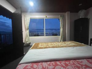 a bedroom with a bed and a large window at Sukhim Farmstay in Mirik