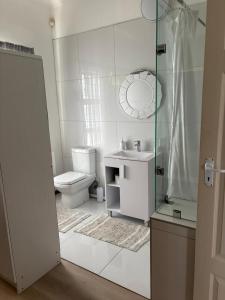 a white bathroom with a toilet and a sink at Sundowner in Yzerfontein