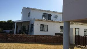 a white house with a brick fence in front of it at Sundowner in Yzerfontein +4 photos