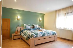 a bedroom with a bed and a green wall at Le Courlis du Ried in Grussenheim