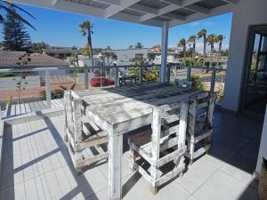 a wooden table on a porch with a view of the ocean at Blouberg Studio Apartments in Cape Town