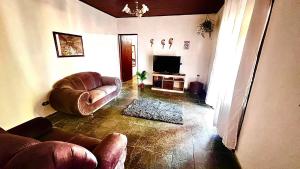 a living room with a couch and a television at Chale da Pousada Curió in Ibiúna
