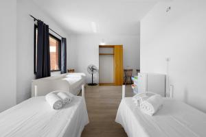 two beds in a room with white walls at Daluef Alloggi in Assemini